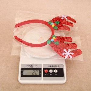 Detailed view of red Christmas reindeer headband with colorful pom-poms on weight scale