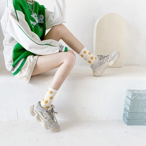 Close-up of white crew socks with yellow smiley face print and soft knit texture