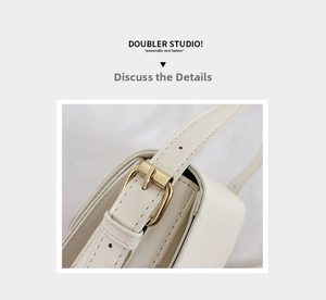 Close-up of adjustable strap with gold-tone buckle on creamy white leather handbag