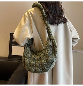 Quilted velvet tote bag in dark green shown from a side view on a model for casual wear