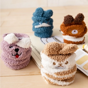 Cozy coral fleece animal socks displayed on wood surface for winter warmth