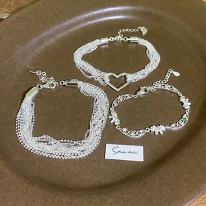 Three elegant layered silver bracelets with heart, bead, and zircon butterfly charms