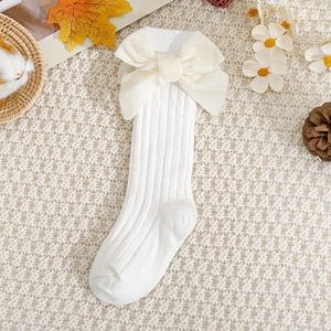 Close-up of baby knee high socks with large velvet bows on warm knit background