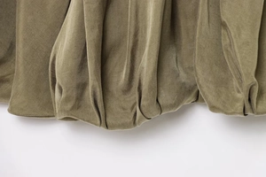 Detailed macro view of the olive green puffer bomber jacket showing pleated bubble hem fabric