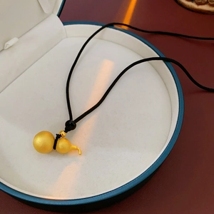 Macro view of a 18K gold-plated gourd hollow pendant on a black rope chain in a gift box