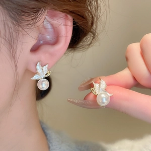 Elegant gold butterfly stud earrings with white pearls for women on model ear