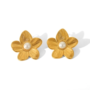 Macro detail of 18K gold textured flower stud earring featuring a white pearl center