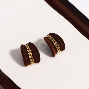 Close-up of brown velvet C-shape earrings with a stylish gold chain wrap detail