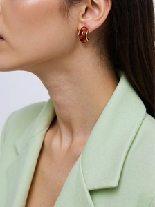 Close-up of amber resin earrings with gold titanium steel plating worn with a chic suit