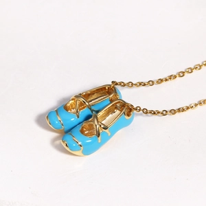 Close-up of blue enamel ballet slipper pendant on a gold dainty necklace chain