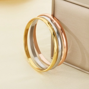 Three-color minimalist titanium steel bangles stacked on a luxury jewelry box