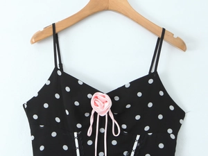Detail des schwarzen Polka-Dot-Tops mit rosa Satinrosen und Schnürband auf Chiffon-Stoff