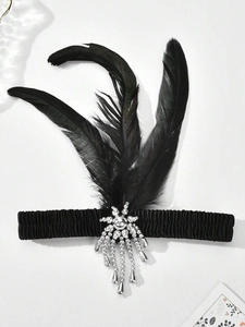Close-up of a 1920s vintage black feather headband with crystal and pearl brooch details