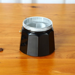 Close-up of black octagonal aluminum moka pot base with brass safety valve detail