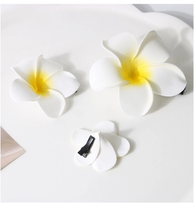 Detailed view of white frangipani hair clips in three sizes with black duckbill clips