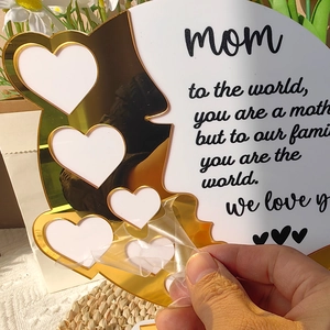 Hand peeling protection film off a gold acrylic heart frame gift for Mom decoration