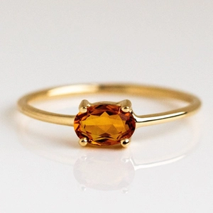 Macro detail of oval orange gemstone on 18k gold plated brass ring with sharp reflections