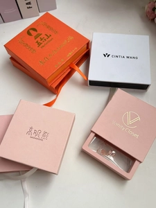 Detalle de cajas de regalo para joyería de alta gama con asas de satén y marca