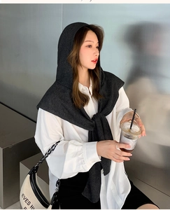 Detailed knit texture of a dark grey hooded scarf shawl on a professional model