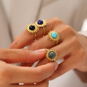 Détail de bagues tournesol dorées avec turquoise et pierres portées par un mannequin