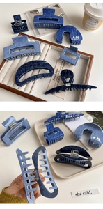 Detailed view of various denim textured hair claws in dark blue shades on a wooden tray