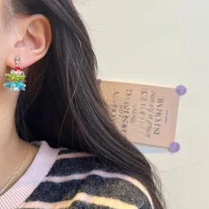 Macro side view of handmade beaded Christmas tree earrings worn on ear with red bow detail