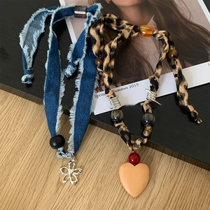 Detail of vintage fabric necklaces with resin beads, denim heart, and leopard print charms