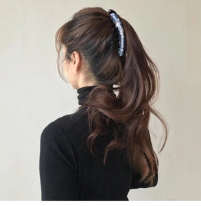 Rear view of a model wearing a large blue patterned banana hair clip for thick hair