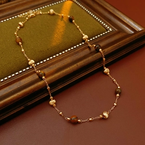 Dettaglio della collana di perle occhio di tigre placcata oro su cornice di legno