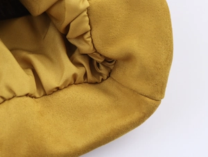 Detail der senfgelben Wildlederjacke mit glänzendem Futter und schwarzem Pflegeetikett