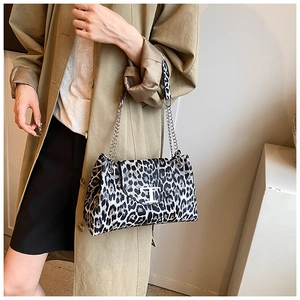 Leopard print crossbody bag with silver chain strap and metal T-buckle on a khaki trench coat