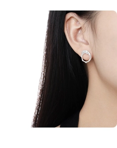 Detail of silver wavy round stud earrings with textured finish worn by a model