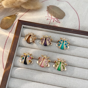 Colorful ladybug brooches with rhinestones and crystals in a wooden jewelry box