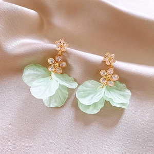 Detailed close-up of French style pearl flower earrings on premium champagne silk fabric