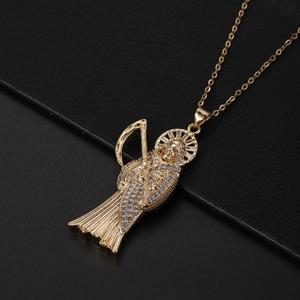 Détail du pendentif Santa Muerte doré serti de zircons brillants sur un fond noir texturé