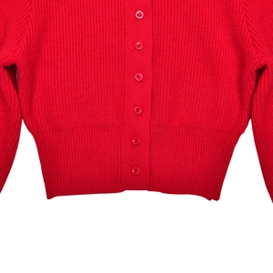 Close-up of red knit cardigan featuring detailed ribbed waist and matching buttons