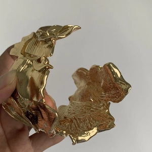 Macro detail of wide gold metal cuff bracelet with artistic irregular leaf leaf textures
