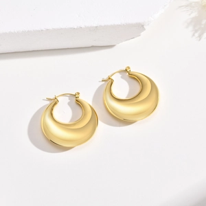 Detail of polished gold-tone hollow teardrop earrings with smooth mirror finish texture