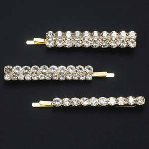 Three-piece gold rhinestone hair clip set with sparkling crystals on a black background
