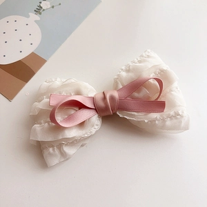 Detailed view of beige chiffon bow hair clip with pink ribbon on clean white background
