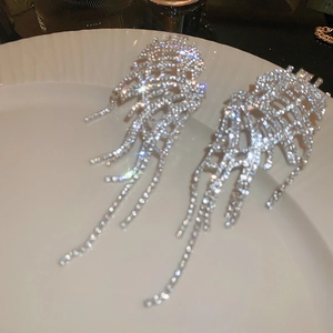 Macro view of silver mesh earrings with waterfall rhinestones on white textured plate