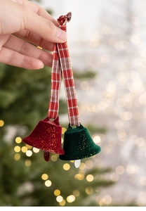 Macro view of red and green flocked Christmas bells with festive ribbon hanging on a tree