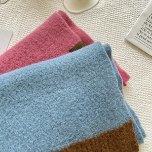 Close-up of soft cashmere-feel knitted scarf texture with stitched brand label details