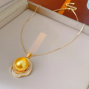 Macro shot of large gold pearl necklace with wavy rhinestone setting on gray jewelry box