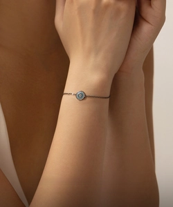Detail of S925 silver black bracelet with blue turquoise evil eye charm on model wrist