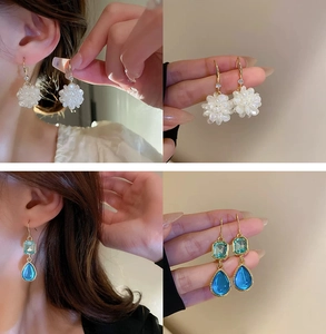 Macro detail of floral pearl tassel earrings and blue crystal drop dangles on gold hooks