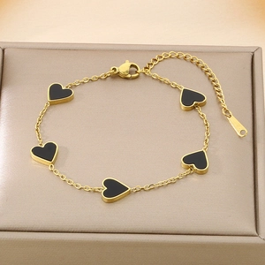 Gold chain bracelet featuring five black heart pendants in a beige jewelry gift box