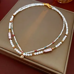 Double-layered beaded necklace featuring baroque pearls and a gold teardrop pendant
