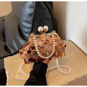 Close-up of sparkling rose gold sequins and pearl clasp on an elegant evening bag
