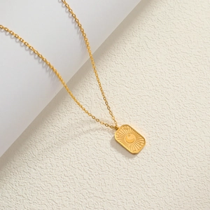 Macro view of 18K gold plated square pendant with embossed sun and moon star details